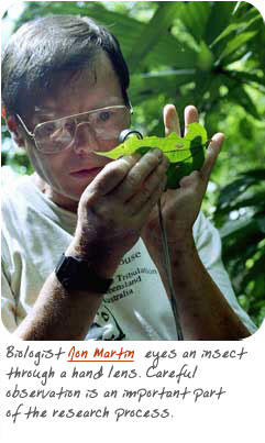 Jon Martin looks at a bug through a hand lens.